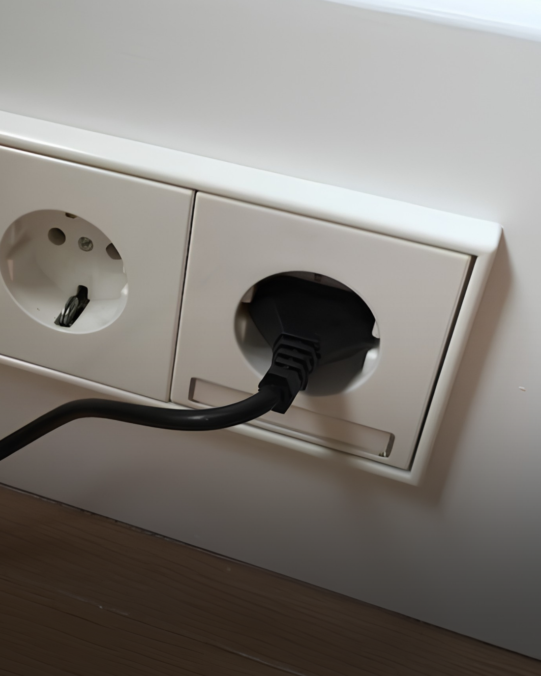 Zwarte stekker aangesloten op een dubbel stopcontact in een woning